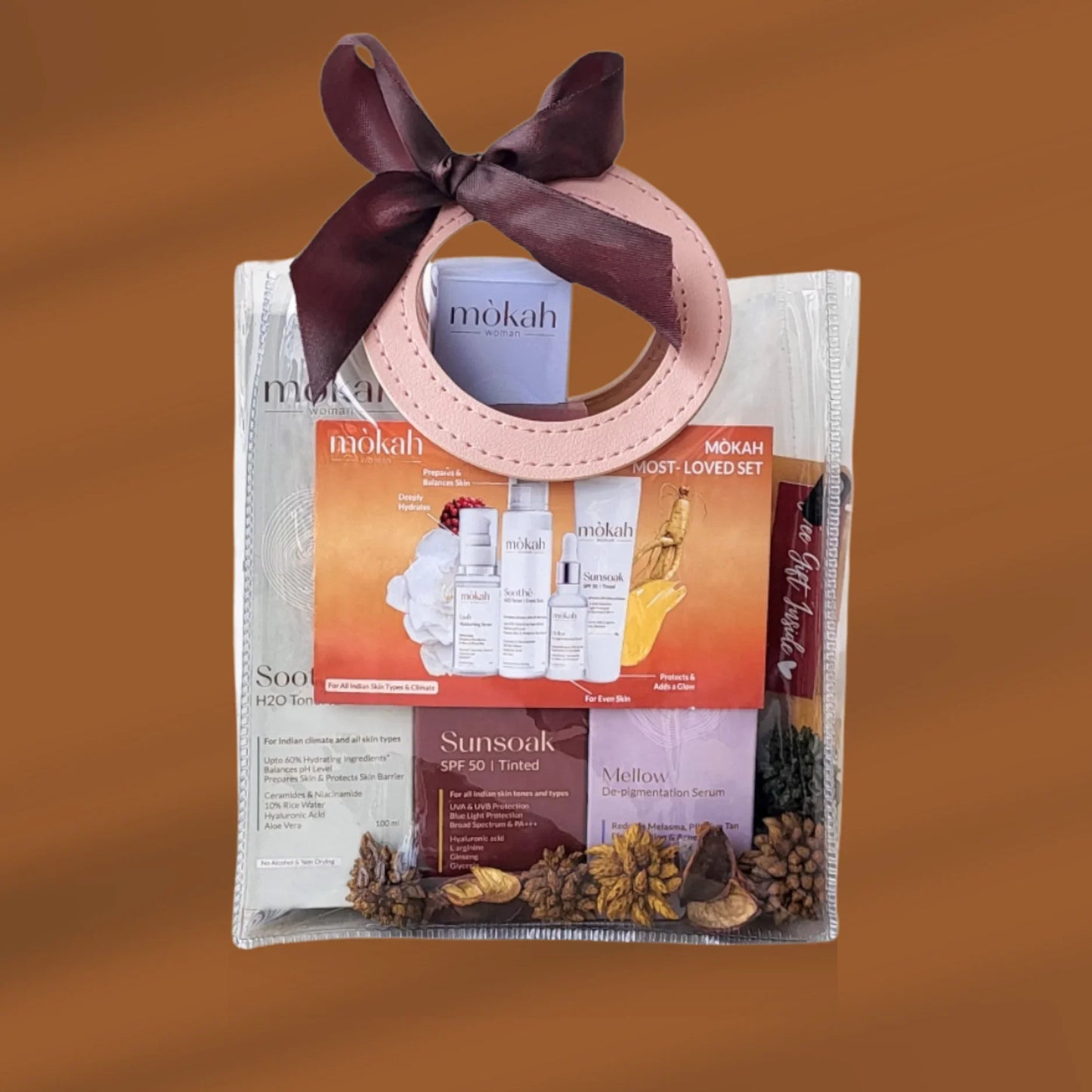 Mòkah Golden Glow Set skincare kit with toner, serum, SPF 50, and travel pouch against brown background