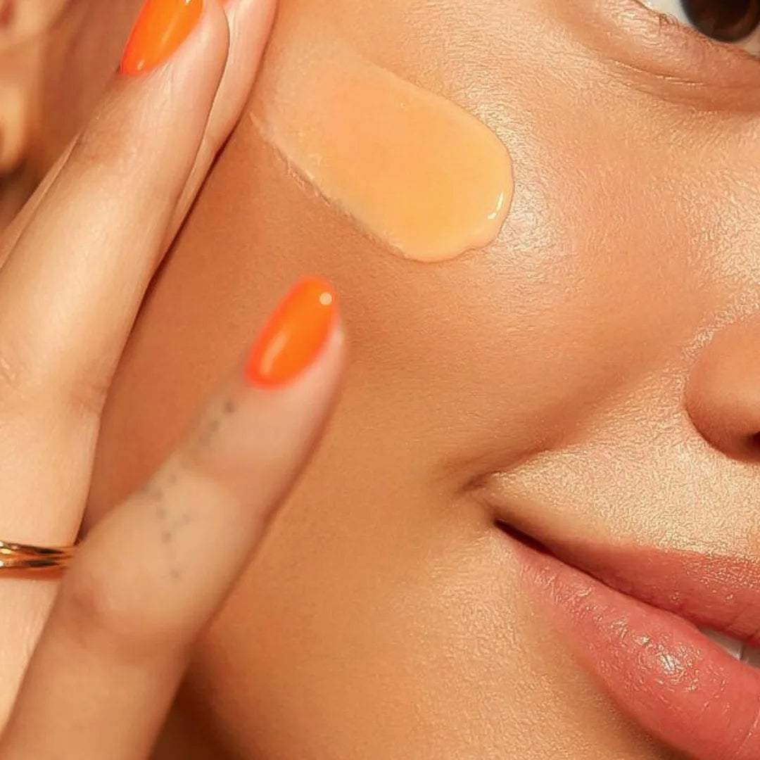 Close-up of a person applying Sunsoak SPF 50 tinted sunscreen on their cheek for UV and blue light protection