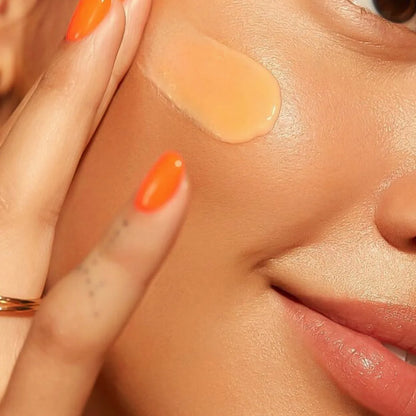 Close-up of a person applying Sunsoak SPF 50 tinted sunscreen on their cheek for UV and blue light protection