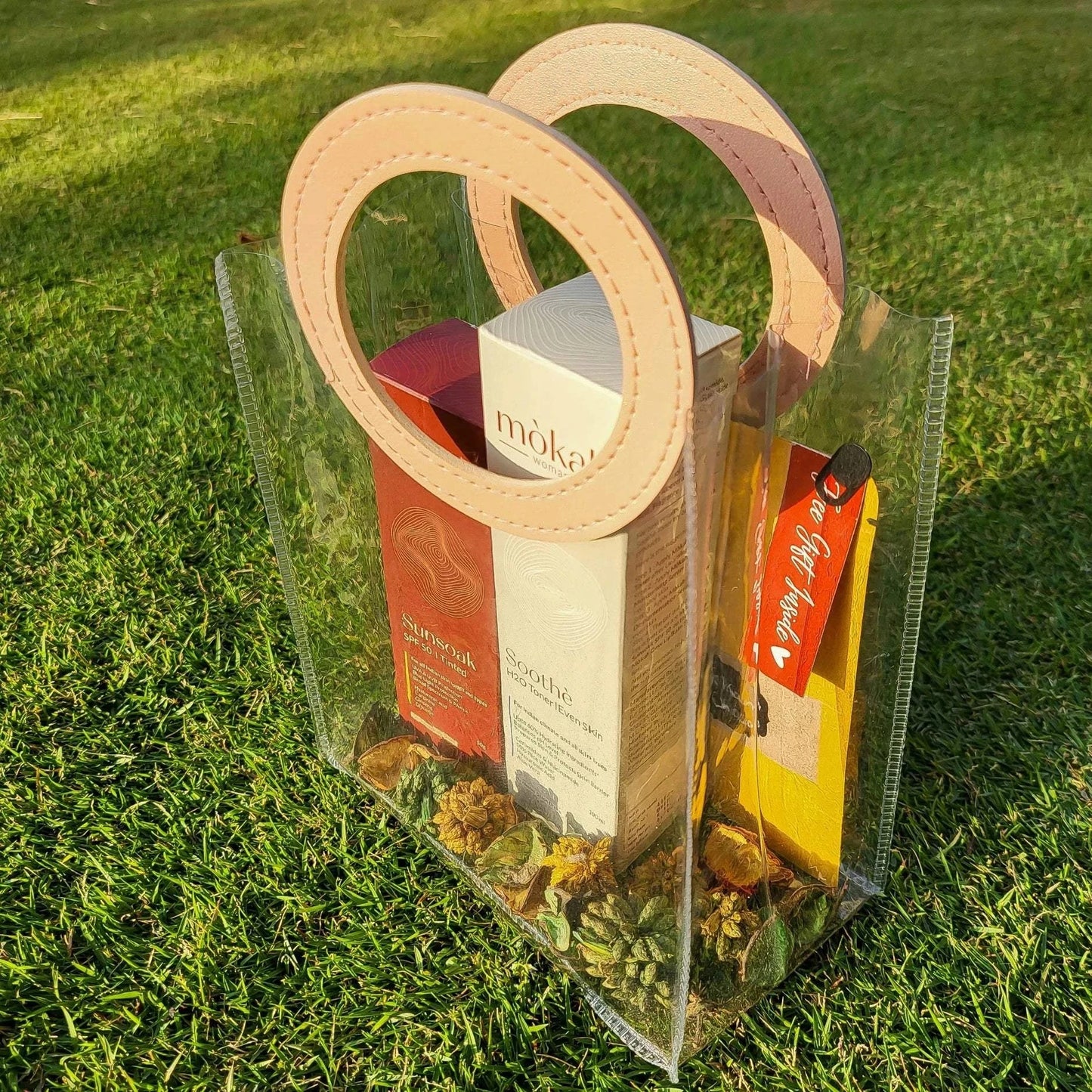 Mòkah Pollution Protect Duo in a stylish clear bag on grass, featuring skin barrier protection products for hydration and sun defense.